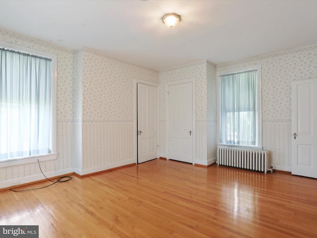 unfurnished bedroom featuring radiator heating unit and light hardwood / wood-style floors