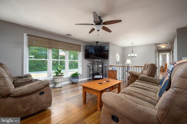 living area with ceiling fan with notable chandelier, light wood-style flooring, and baseboards