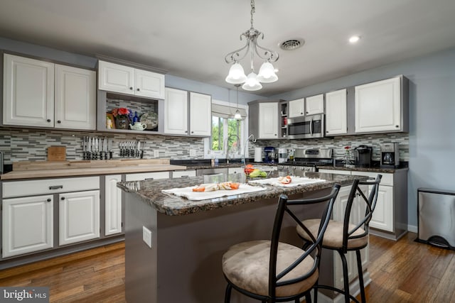 kitchen with white cabinets, visible vents, stainless steel appliances, and a center island