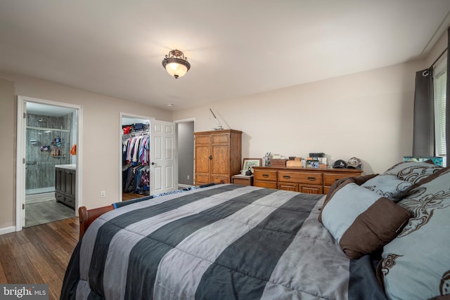 bedroom featuring dark wood-style flooring, a closet, a spacious closet, ensuite bathroom, and baseboards