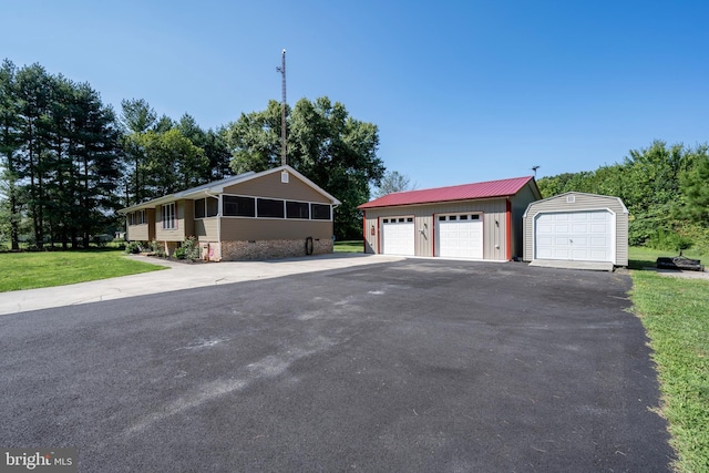 view of front of house featuring a garage, a front lawn, and an outdoor structure