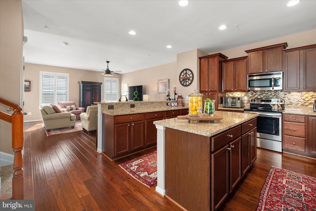 kitchen featuring open floor plan, appliances with stainless steel finishes, dark wood-type flooring, and a center island