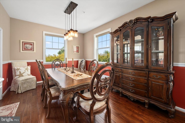 dining area with a wealth of natural light, a notable chandelier, dark wood finished floors, and baseboards