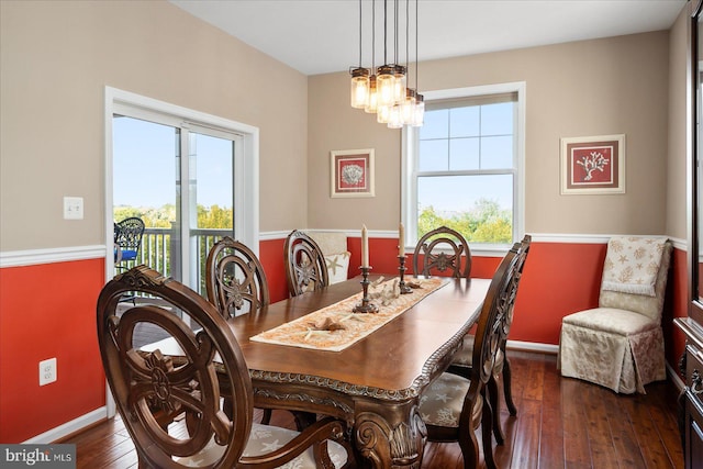 dining area featuring dark wood-style flooring, a notable chandelier, and baseboards