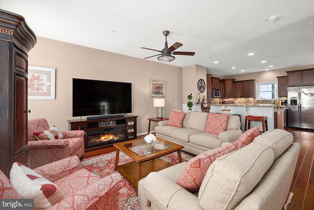 living area with recessed lighting, a glass covered fireplace, wood finished floors, and ceiling fan