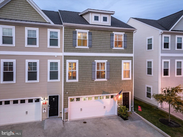 townhome / multi-family property with a garage, roof with shingles, and driveway