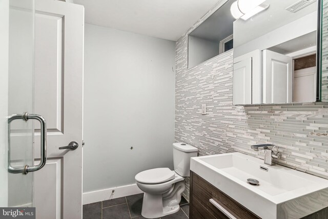 bathroom with tile patterned flooring, toilet, vanity, and backsplash