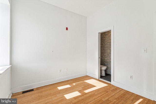 unfurnished bedroom featuring connected bathroom and light wood-type flooring