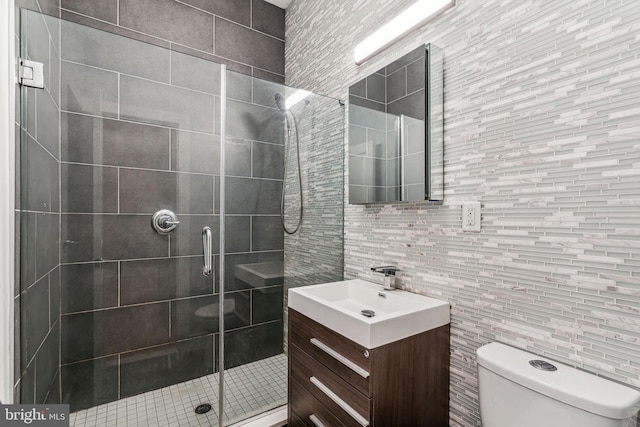 bathroom with toilet, vanity, an enclosed shower, and tile walls