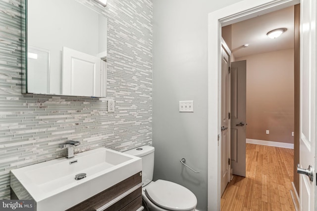 bathroom with decorative backsplash, vanity, wood-type flooring, tile walls, and toilet