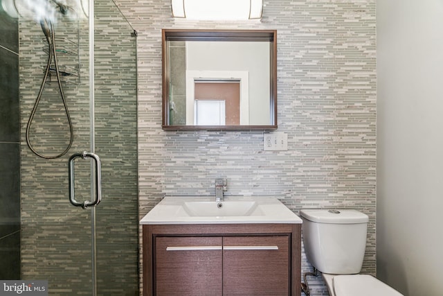 bathroom featuring an enclosed shower, toilet, and vanity