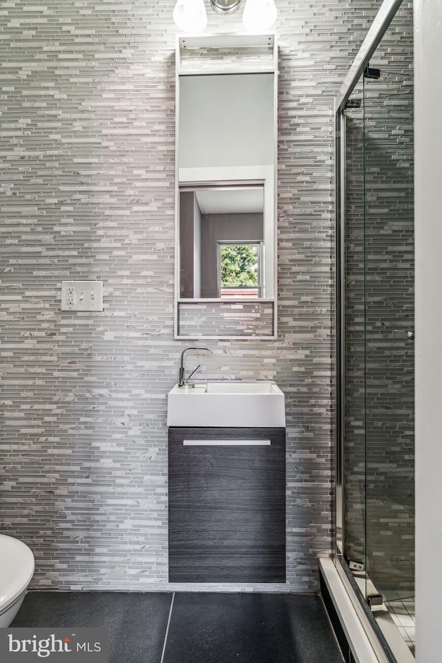 bathroom featuring a shower with shower door, toilet, vanity, and tile walls