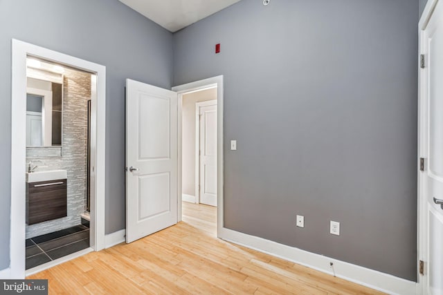 unfurnished bedroom featuring ensuite bath and light wood-type flooring