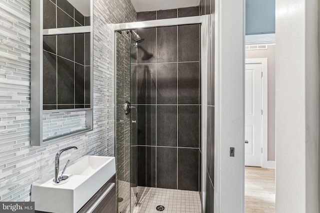 bathroom with a shower with shower door, hardwood / wood-style flooring, and vanity