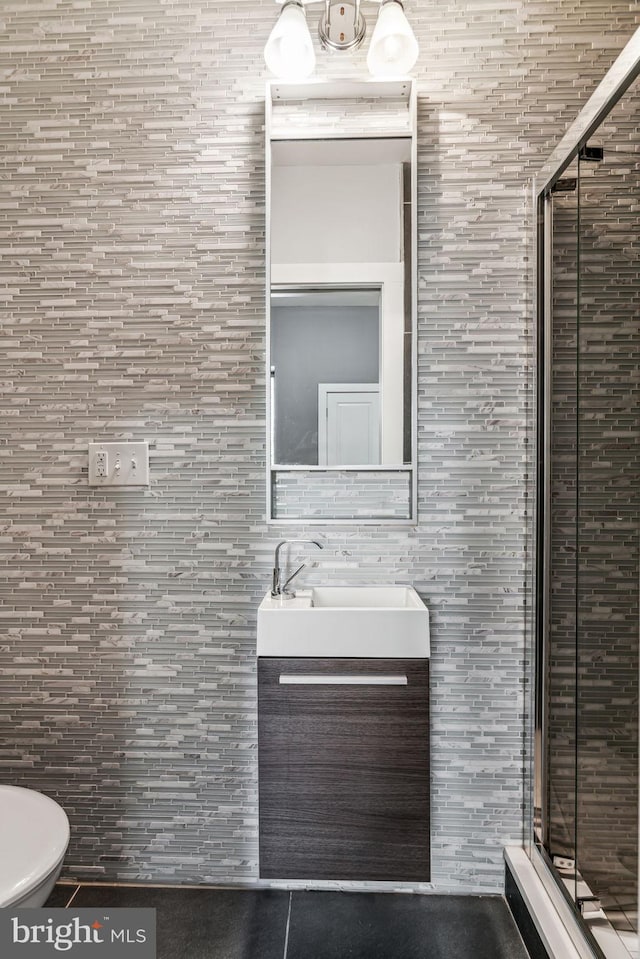 bathroom featuring tile walls, toilet, vanity, and a shower with door