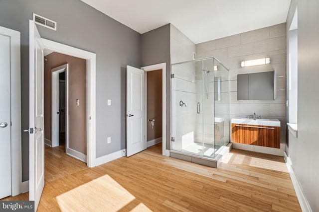 bathroom with a shower with shower door, tile walls, vanity, and wood-type flooring