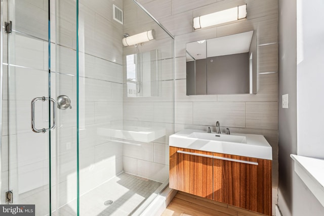 bathroom with tile walls, an enclosed shower, and vanity