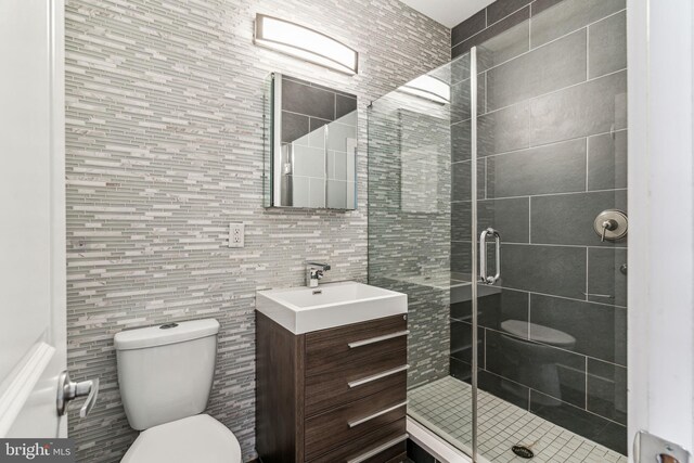 bathroom featuring tile walls, vanity, walk in shower, and toilet