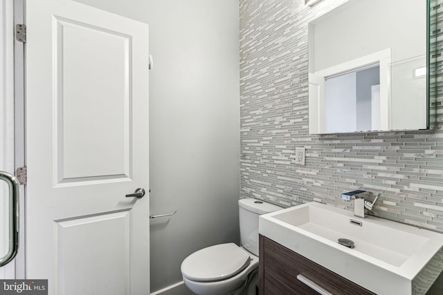 bathroom featuring toilet, vanity, and tasteful backsplash