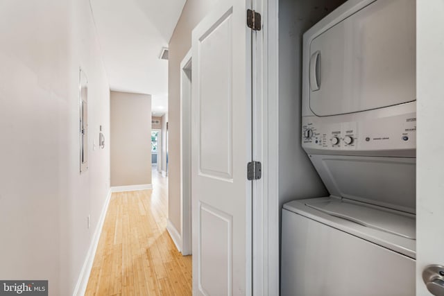 clothes washing area with light wood-type flooring and stacked washer / dryer