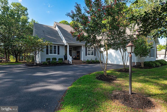 view of front of home featuring a front lawn, driveway, a shingled roof, and an attached garage