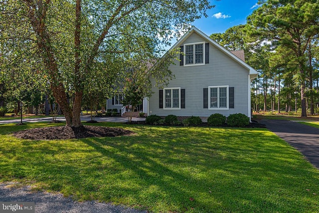 view of front of house featuring aphalt driveway and a front lawn