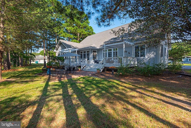 rear view of property featuring a shingled roof, a yard, a deck, and a pergola