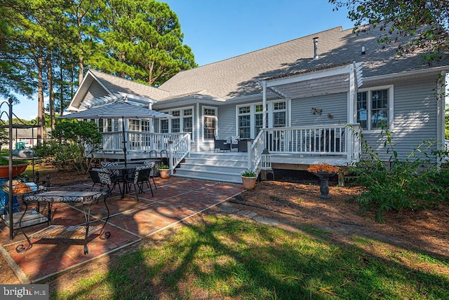 back of house featuring a shingled roof, a wooden deck, and a pergola