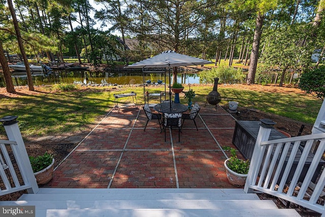 view of patio featuring outdoor dining space, a water view, and a gazebo