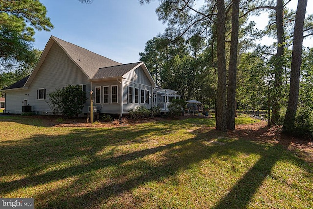 view of home's exterior featuring central AC unit, a lawn, and a shingled roof