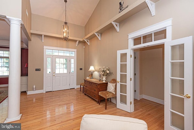 entryway with high vaulted ceiling, light hardwood / wood-style floors, and decorative columns