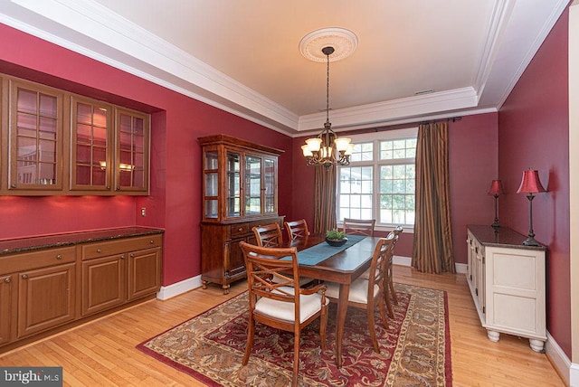 dining area featuring light wood-type flooring, an inviting chandelier, and crown molding