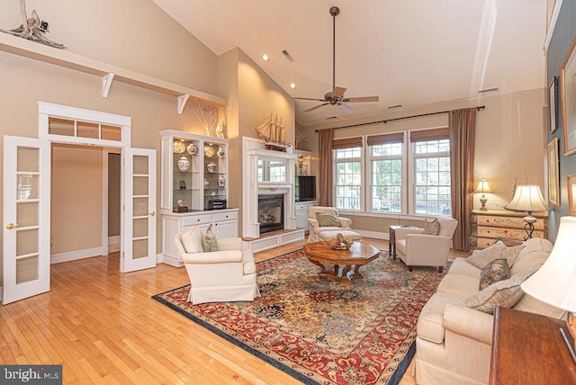 living room with ceiling fan, light wood-type flooring, and high vaulted ceiling