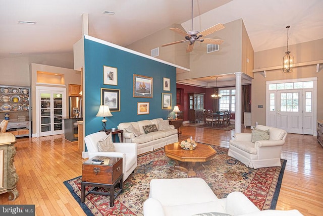 living room featuring high vaulted ceiling, ceiling fan with notable chandelier, and light hardwood / wood-style floors