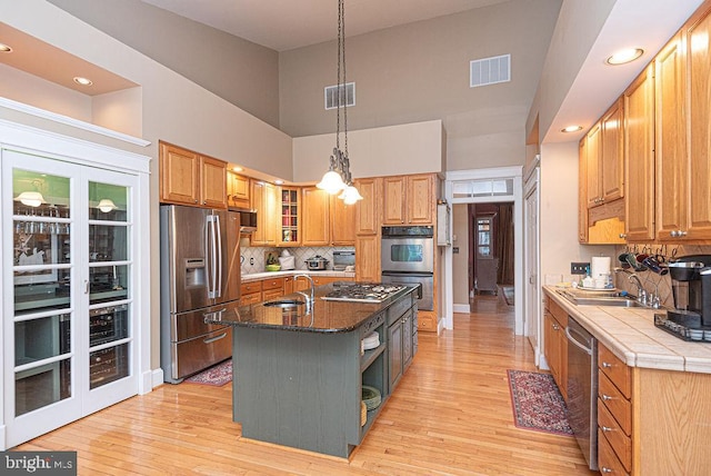 kitchen featuring appliances with stainless steel finishes, a center island with sink, light hardwood / wood-style floors, and sink