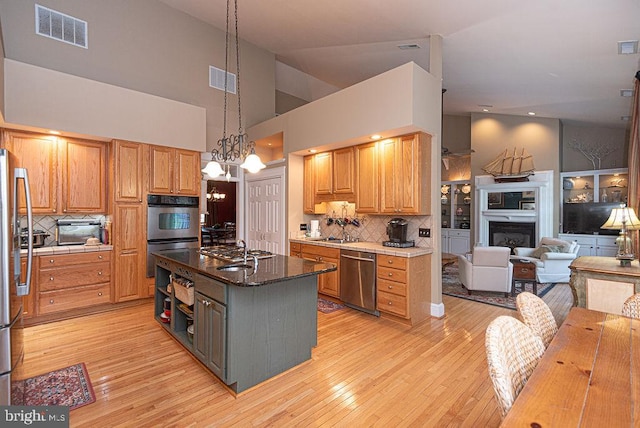 kitchen with backsplash, stainless steel appliances, decorative light fixtures, light hardwood / wood-style flooring, and a kitchen island