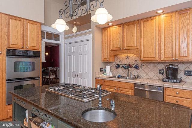 kitchen with tasteful backsplash, stainless steel appliances, a sink, and decorative light fixtures