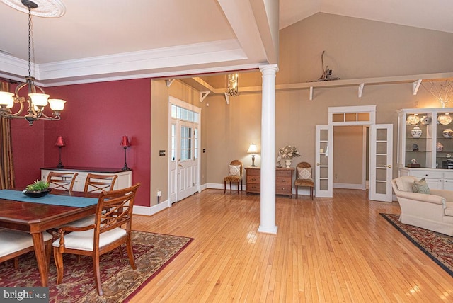 dining space with french doors, a notable chandelier, ornamental molding, wood finished floors, and ornate columns