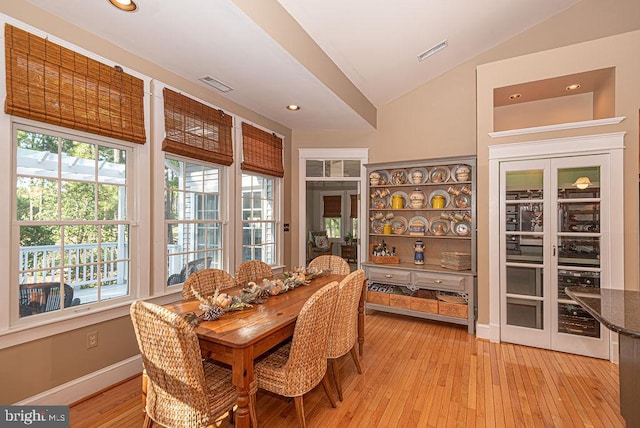 dining area with light wood-type flooring and lofted ceiling