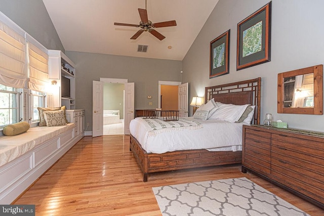 bedroom with ceiling fan, high vaulted ceiling, light hardwood / wood-style floors, and ensuite bath