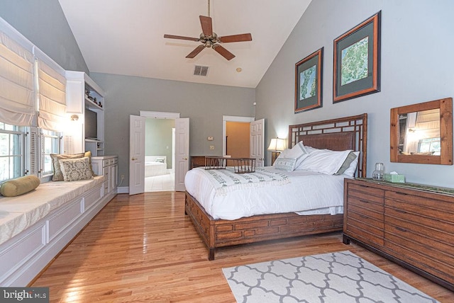 bedroom with ceiling fan, high vaulted ceiling, ensuite bath, and light wood-type flooring