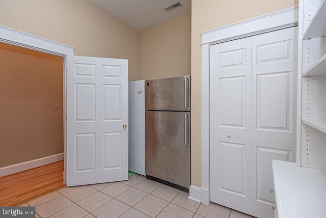 kitchen with light countertops, freestanding refrigerator, visible vents, and light tile patterned floors