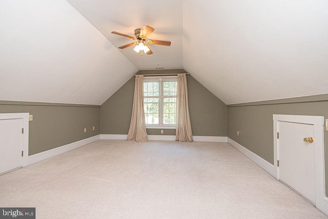 additional living space featuring light carpet, ceiling fan, baseboards, and vaulted ceiling