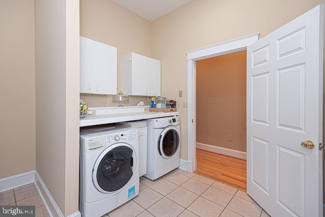 clothes washing area with independent washer and dryer, light tile patterned flooring, cabinet space, and baseboards