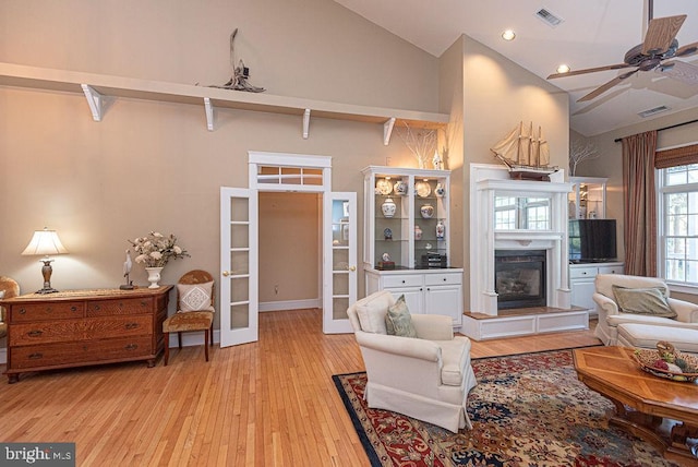 living room with light hardwood / wood-style floors, high vaulted ceiling, and ceiling fan