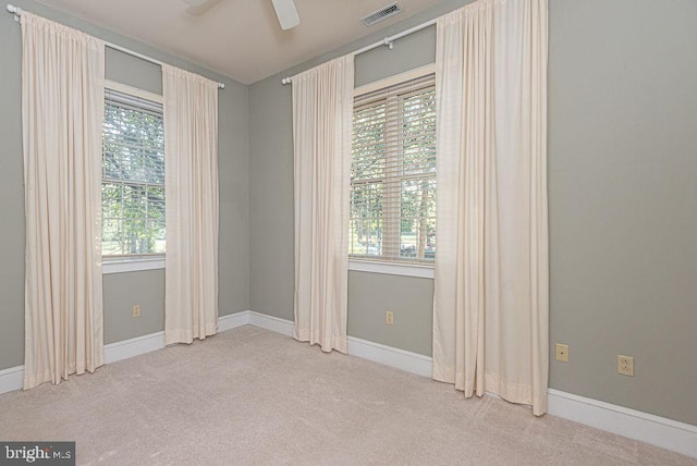 unfurnished room featuring plenty of natural light, ceiling fan, and carpet floors