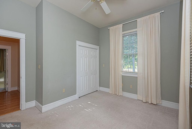 unfurnished bedroom featuring light carpet, a ceiling fan, baseboards, and a closet