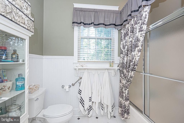 bathroom with shower / bath combination with glass door, toilet, and tile patterned floors