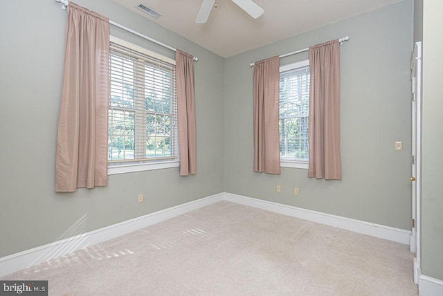 empty room featuring light carpet, baseboards, visible vents, and a ceiling fan