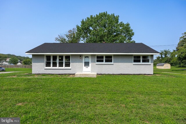 single story home with a front yard and a storage unit